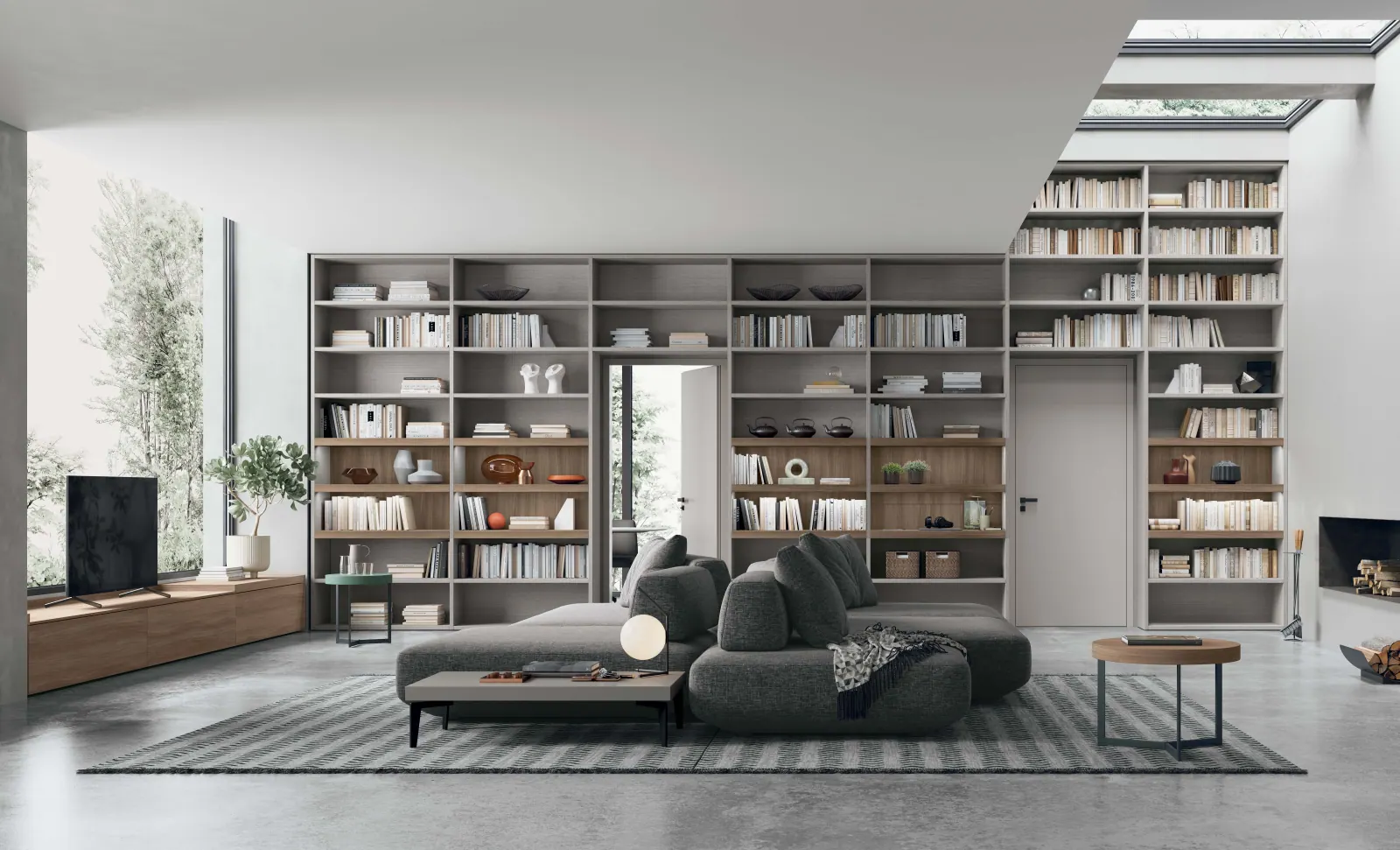 Soggiorno con libreria a tutta parete in legno chiaro e divano modulare grigio