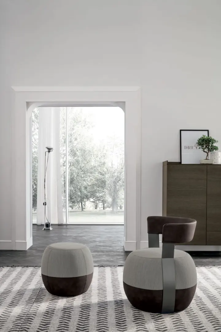 Pouf e poltroncina bicolore rivestiti in tessuto, in un ingresso luminoso