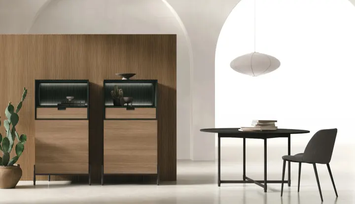 Madie alte Time in legno con ante vetrate e interno illuminato, accanto al tavolo da pranzo