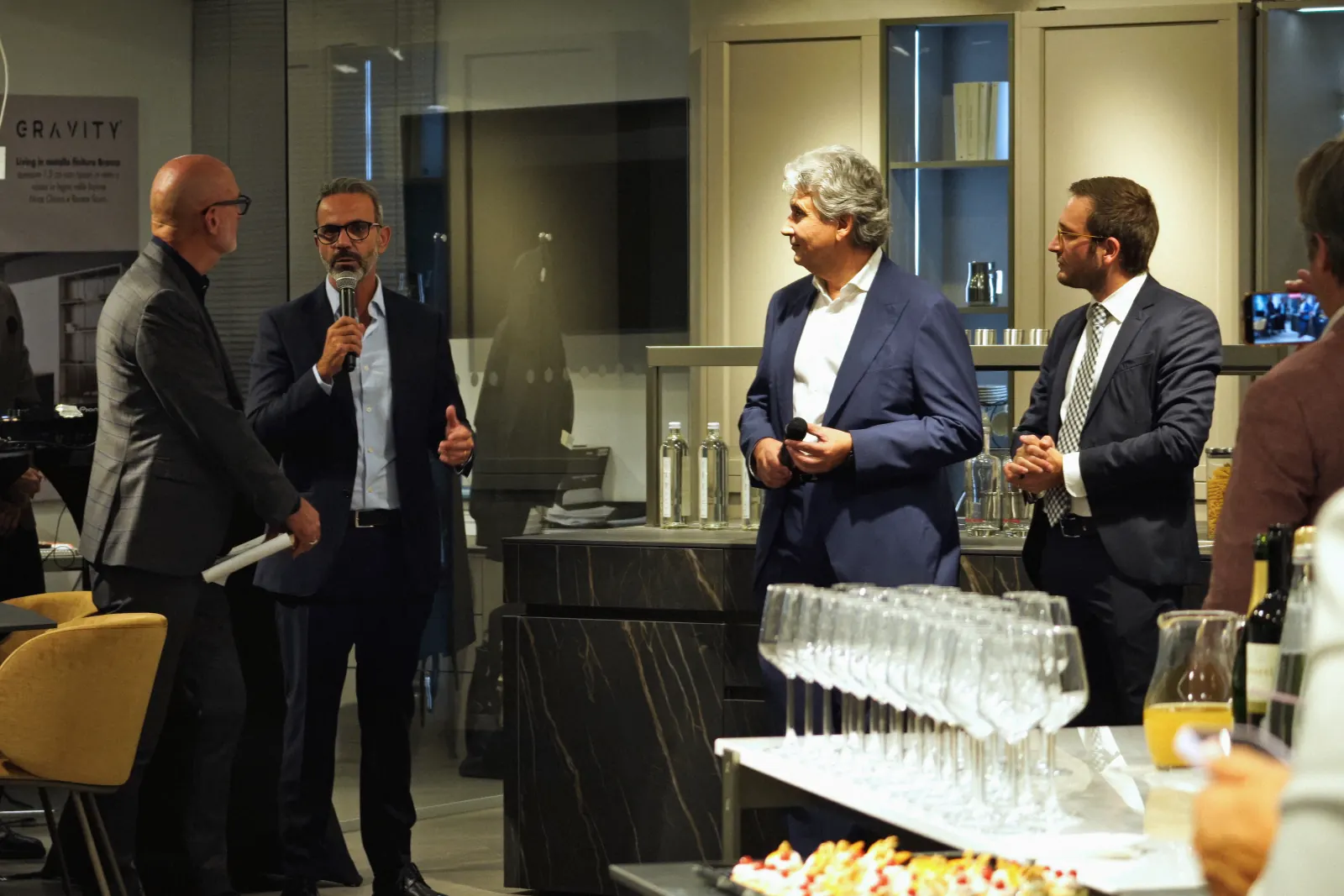 Un momento dei discorsi durante la serata di apertura, con gli ospiti riuniti attorno al bancone