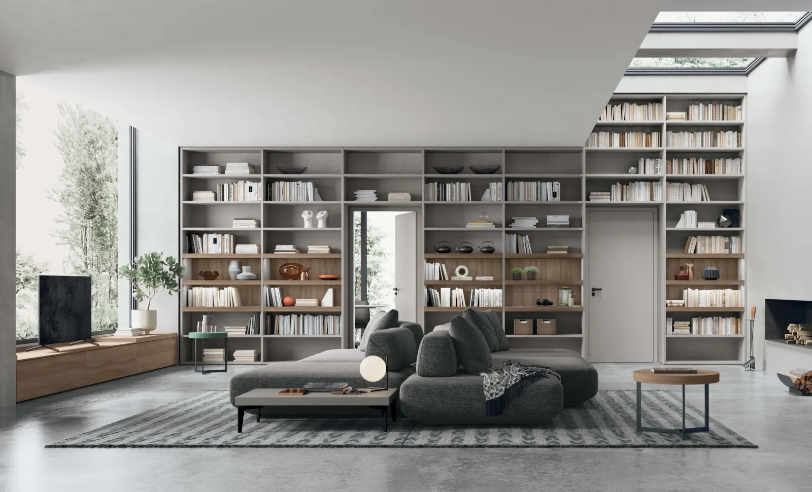 Soggiorno con libreria a tutta parete in legno chiaro e divano modulare grigio
