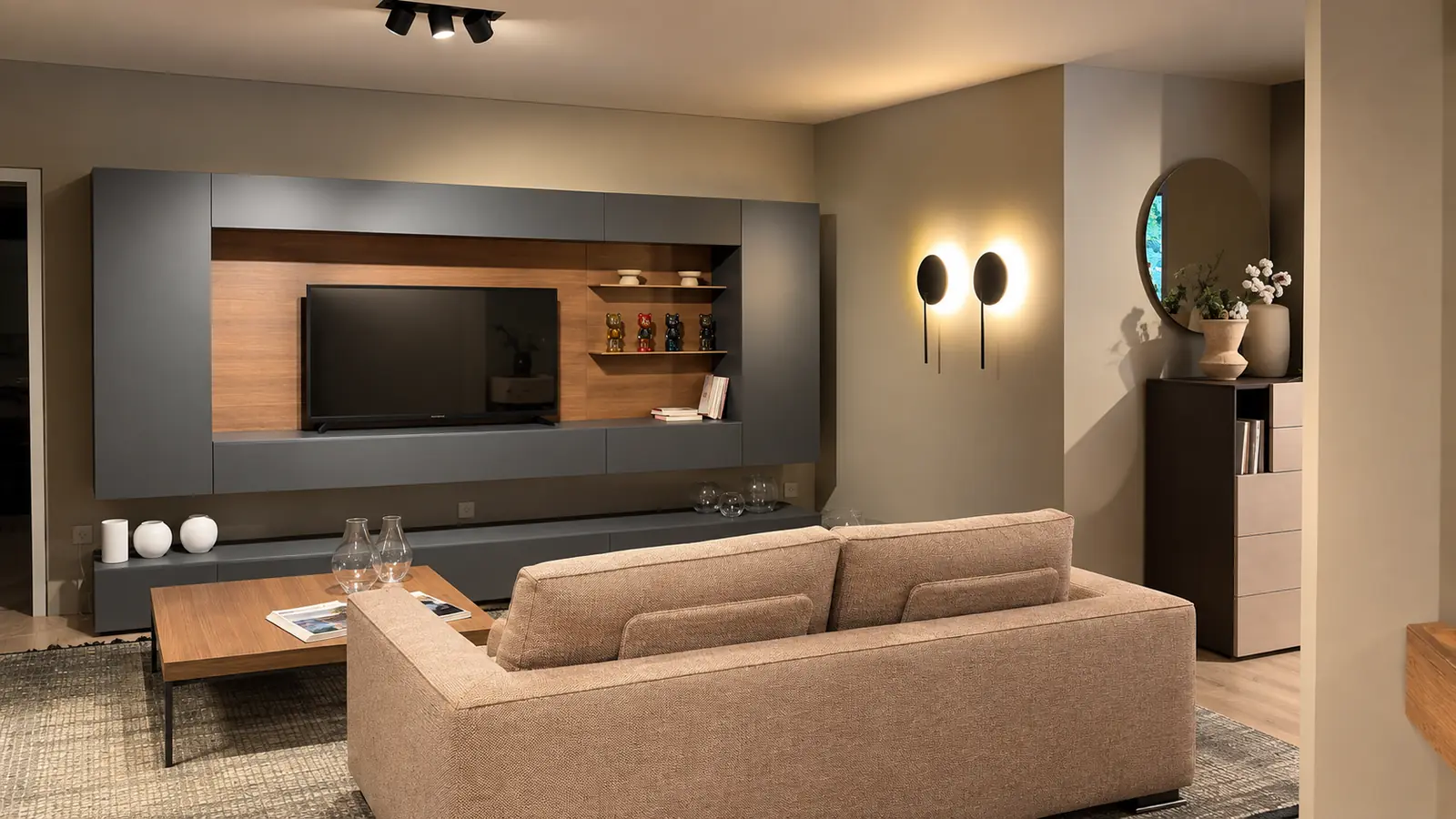 Salotto dello showroom con parete attrezzata in legno, televisore e divano