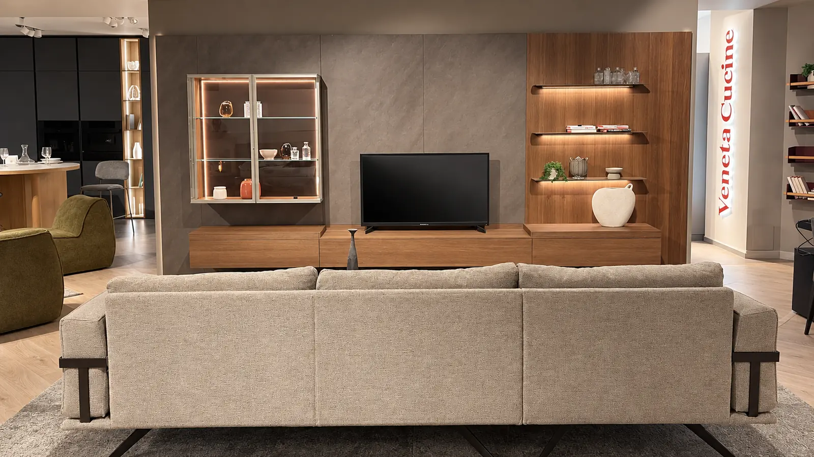 Divano di fronte a una parete attrezzata con vetrine illuminate e televisore